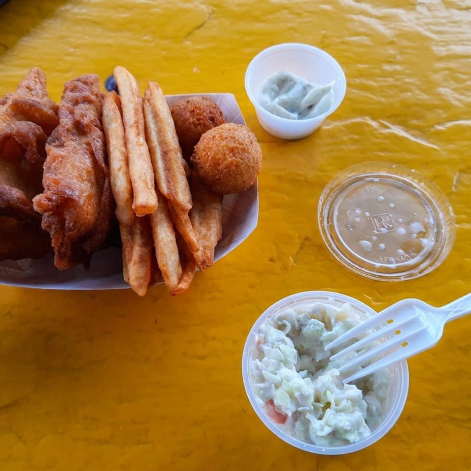 Plate of assorted fried snacks with dipping sauces and creamy salad on a yellow table.